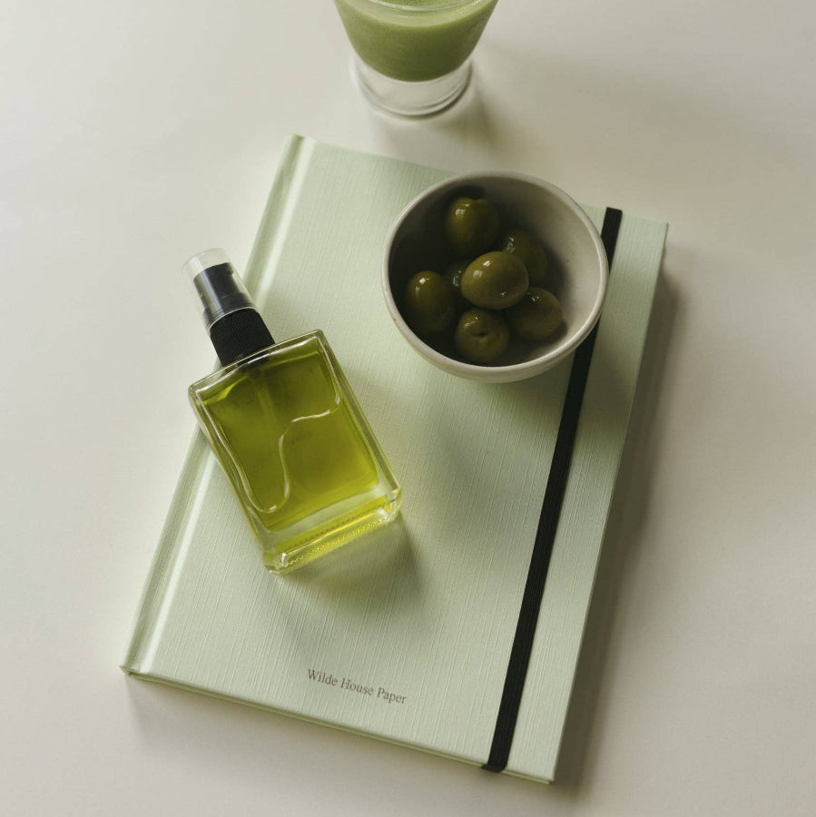 Green bottle, glass of green smoothie, and bowl on a notebook