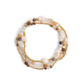 Stack of beaded bracelets with gold accents on a white background