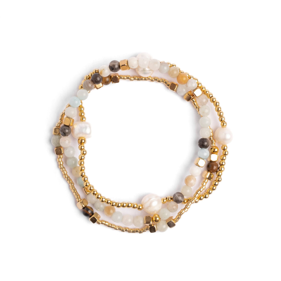 Stack of beaded bracelets with gold accents on a white background
