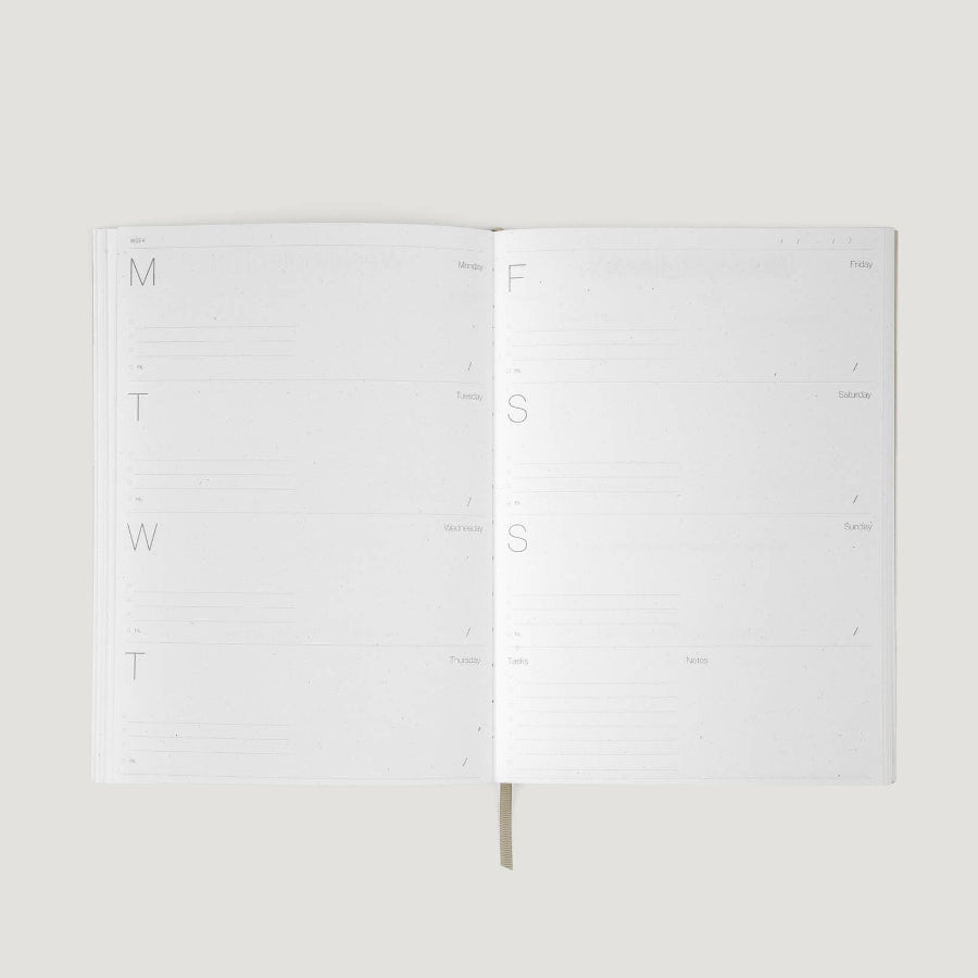 White planner with days of the week on a light gray background
