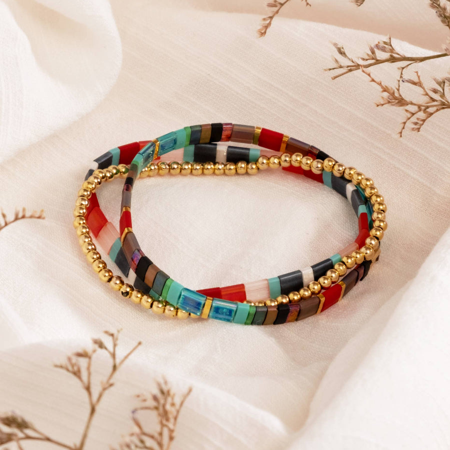 Multicolored beaded bracelet with gold accents on a light fabric background