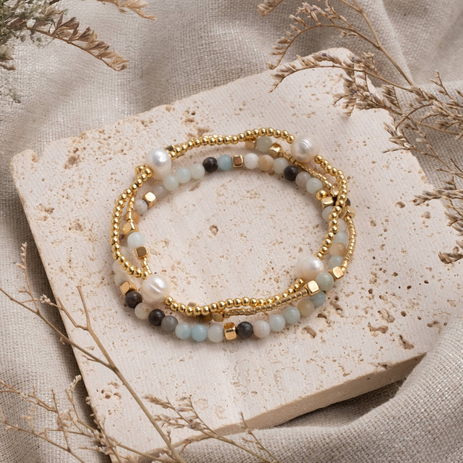 Two beaded bracelets on a stone surface with a neutral background
