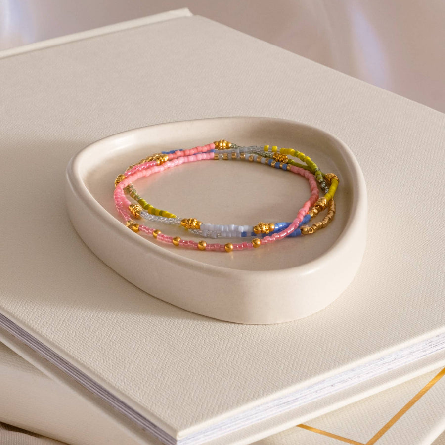 Set of colorful beaded bracelets on a white dish with a white surface underneath